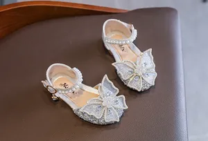 Close-up of silver glitter girls princess shoes with large butterfly bow and pearls