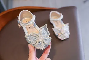 Close-up of girl's princess sandals with rhinestone butterfly and pearl strap
