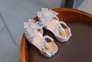 Close-up of girls' silver glitter princess sandals with lace bow and pearl straps.