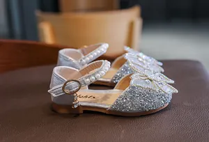 Close-up detail of sparkly silver girls' sandals featuring pearls and a beautiful butterfly bow