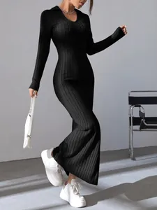 Full-length view of a black ribbed long-sleeved dress styled with white sneakers
