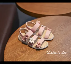 Detail view of pink girls flower sandals on wooden table with elegant floral accents