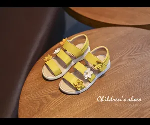 Close-up of yellow girl's summer sandals with white and yellow 3D floral decorations