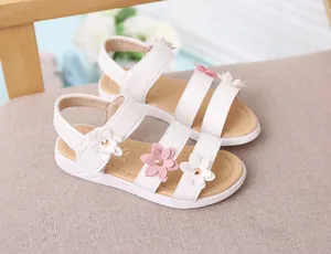 Detalle de sandalias blancas de princesa para niña con flores en 3D y cierre de velcro.