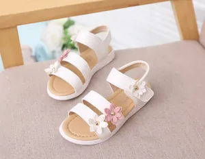 Detalle de sandalias blancas para niña con flores decorativas en color rosa y blanco