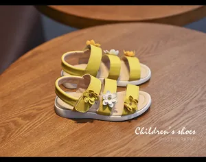 Close-up view of yellow children's sandals featuring exquisite 3D floral appliques on straps