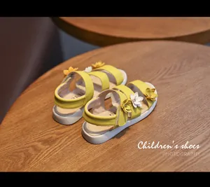 Close-up view of yellow children's sandals with decorative 3D flowers and white rubber soles