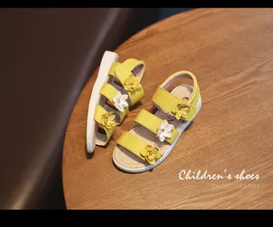 Close-up of yellow girl's sandals featuring delicate 3D floral decorations and Velcro