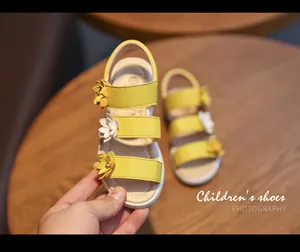 Close-up of yellow girls' sandals with floral decorations on a wooden background