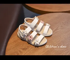 Close-up detail of white girls' sandals featuring elegant 3D pink and white floral accents