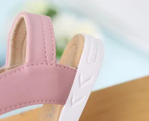 Detalle de la tira rosa y suela blanca con texto Fashion en una sandalia de niña.