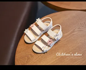 Close-up view of white girl's princess sandals decorated with pink and white flowers.