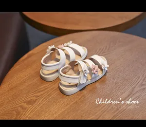 Detailed view of white girls' sandals with delicate pink and white flower decorations