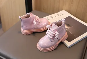 Pink glittery children's Martin boots with side zipper and lace-up design in a studio setting