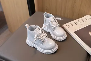 Close-up of glittery silver children's Martin boots with side zipper and lace-up detail.