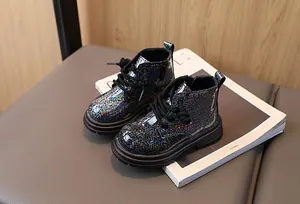 Detailed view of shiny black holographic glitter children's Martin boots on a book.