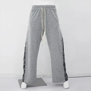 Vue détaillée du jogging hip-hop gris pour homme avec panneaux paisley et boutons-pression.