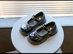 Close-up top view of black patent leather Mary Jane shoes for girls on a grey display