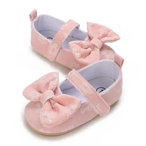Nahaufnahme von rosa geblümten Babyschuhen für Mädchen mit einer großen Schleife