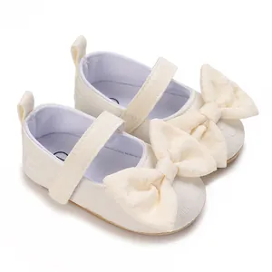 Detail von cremeweißen Baby-Lauflernschuhen für Mädchen mit einer großen dekorativen Schleife