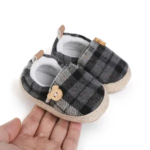 Close-up detail of plaid baby walking shoes with a cute bear-shaped wooden button