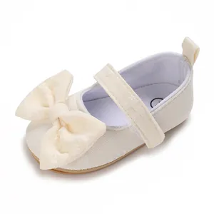 Nahaufnahme der cremefarbenen Stofftextur und der großen Schleife am Baby-Lauflernschuh.
