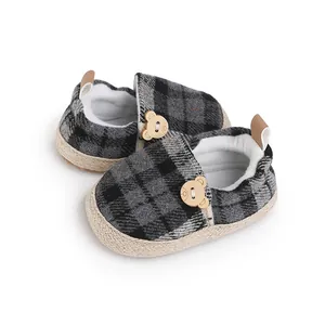 Detalle de zapatos de bebé a cuadros con lindo botón de oso y forro interior suave