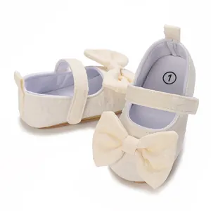Detailansicht weicher Lauflernschuhe für Babymädchen mit eleganten cremefarbenen Schleifen.