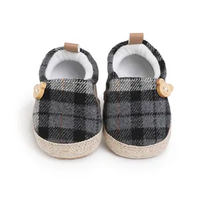 Vista de detalle de zapatos de bebé a cuadros con adorno de oso de madera y suela de yute