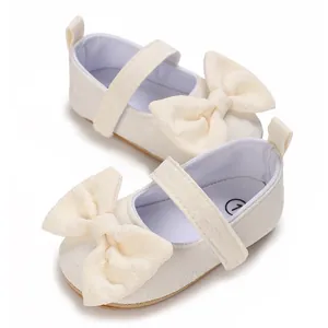 Nahaufnahme von cremefarbenen Baby-Lauflernschuhen für Mädchen mit großer Schleife