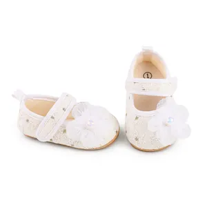 Nahaufnahme von weißen Spitzen-Prinzessinenschuhen für Babys mit Blumendeko