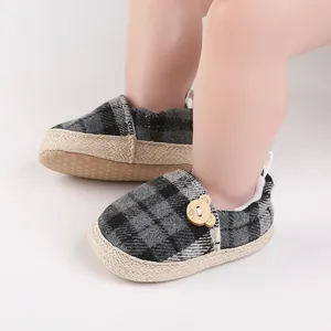 Primer plano de zapatos de cuadros para bebé con oso decorativo y suela suave