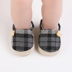 Detalle de zapatos de bebé a cuadros con botones de oso de madera y suela de yute.