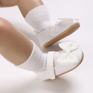 Nahaufnahme weißer Baby-Lauflernschuhe für Mädchen mit Schleifen und weicher Sohle