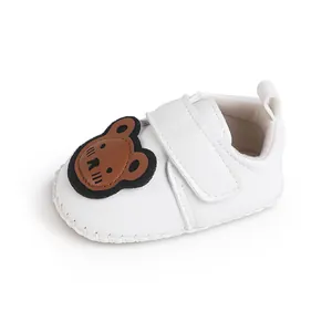 Detailansicht weißer Baby-Lauflernschuh mit süßem braunem Bären-Patch und Klettverschluss