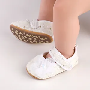 Nahaufnahme von weißen Spitzen-Prinzessinnenschuhen für Babys mit Blumenverzierung