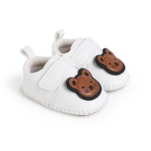 Nahaufnahme von weißen Baby-Lauflernschuhen mit süßem Bären-Aufnäher.