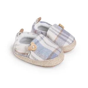 Detalle de zapatos para bebé con cuadro azul y decoración de botón de oso lindo