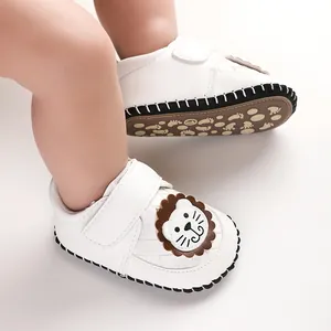 Close-up of white baby walking shoes with cartoon lion and non-slip soles.