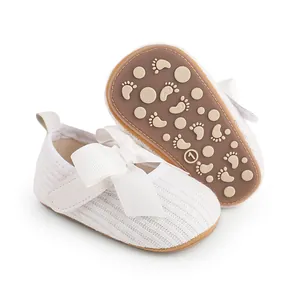 Détail des chaussures de marche blanches pour bébé avec un grand nœud et semelle antidérapante.