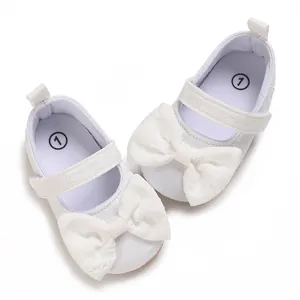Detail einer weißen Schleife aus Spitze auf weichen Lauflernschuhen für Mädchen.