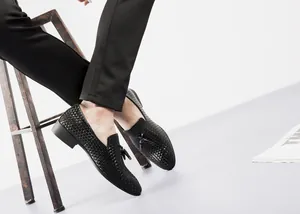 Detailansicht eleganter schwarzer geflochtener Herren-Loafer mit Quasten und Textur.