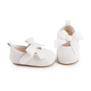 Détail en gros plan de chaussures de fête tricotées blanches pour bébé fille avec de grands nœuds