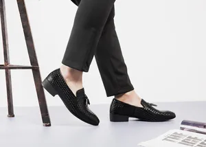 Detailansicht schwarzer geflochtener Herren-Slipper mit Quasten und schwarzer Hose