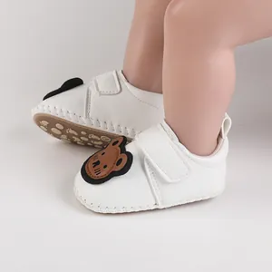 Weiße Baby-Lernlaufschuhe mit süßem Bären-Patch und weicher Sohle im Detail.