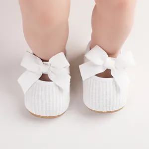 Gros plan de chaussures de fête blanches pour bébés filles avec de grands nœuds côtelés