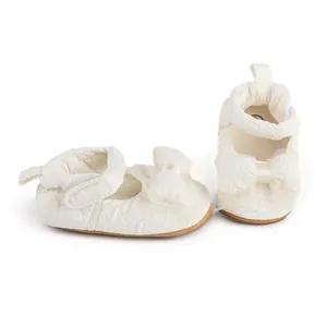 Vue détaillée des chaussures de marche pour bébé blanches à volants avec d'élégants nœuds en tulle.