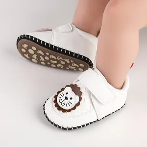 Detail of white infant walking shoes featuring a cute lion applique and anti-slip sole