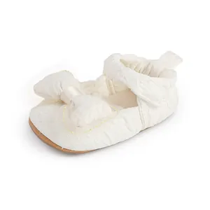 Gros plan d'une chaussure de marche blanche pour bébé avec un détail de nœud texturé