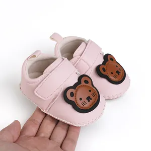 Detailansicht der niedlichen rosa Baby-Lauflernschuhe mit Cartoon-Bär-Design in der Hand